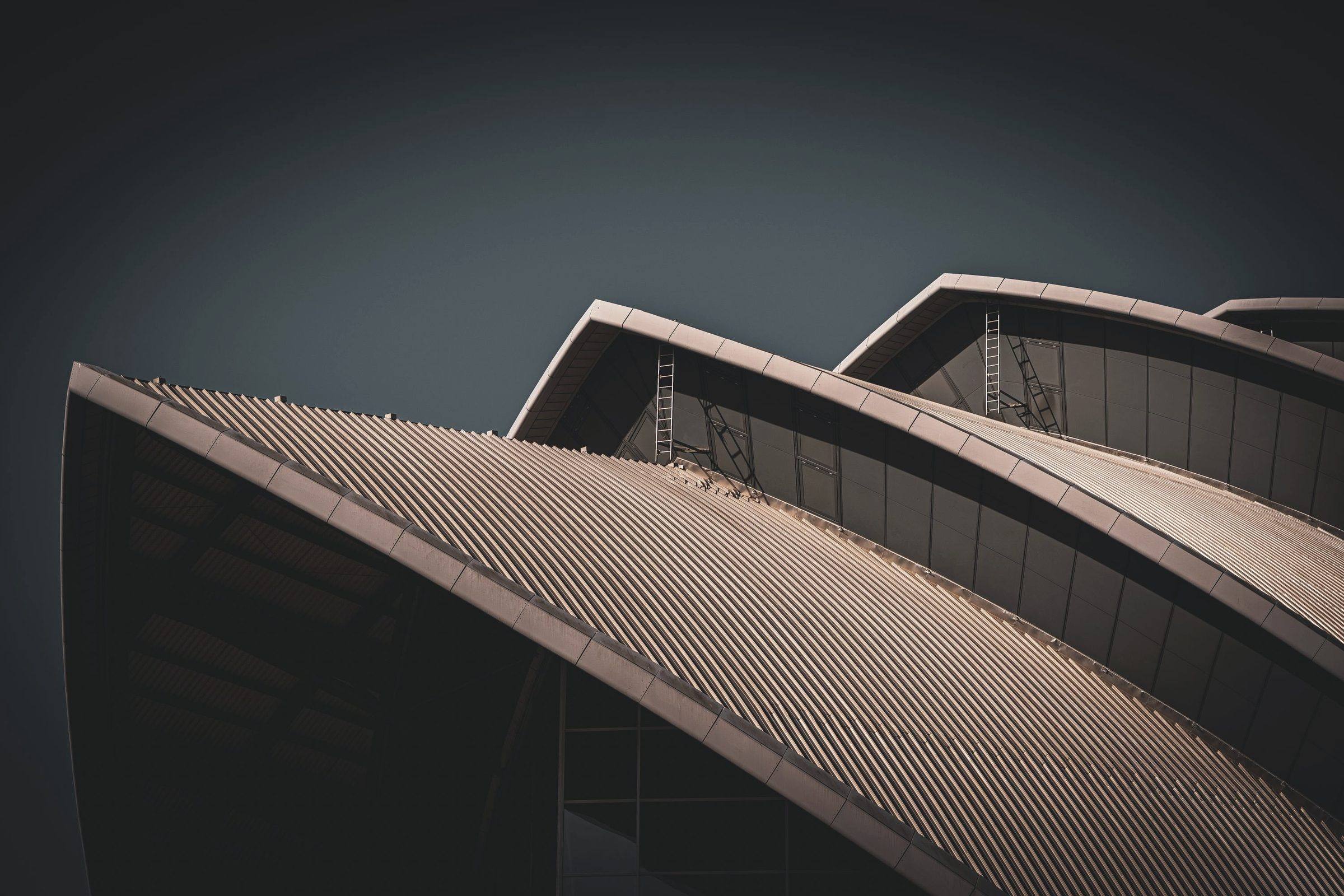 Curved standing-seam metal roof against a dark sky