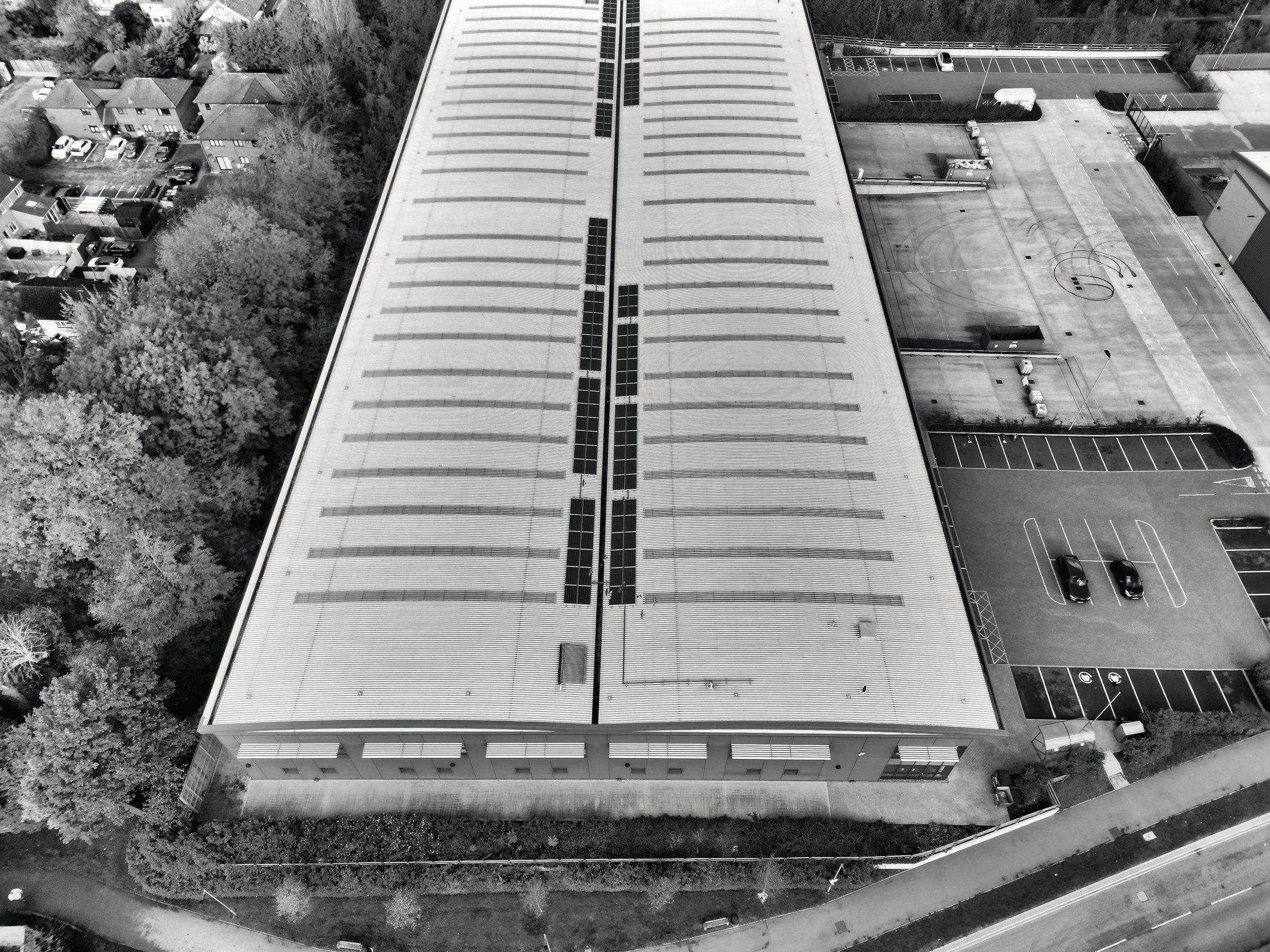 Aerial view of a long warehouse roof, in black and white